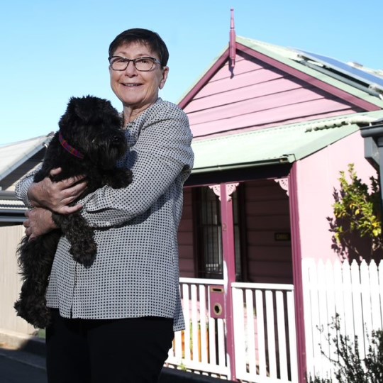 Woman carrying a dog outside a home